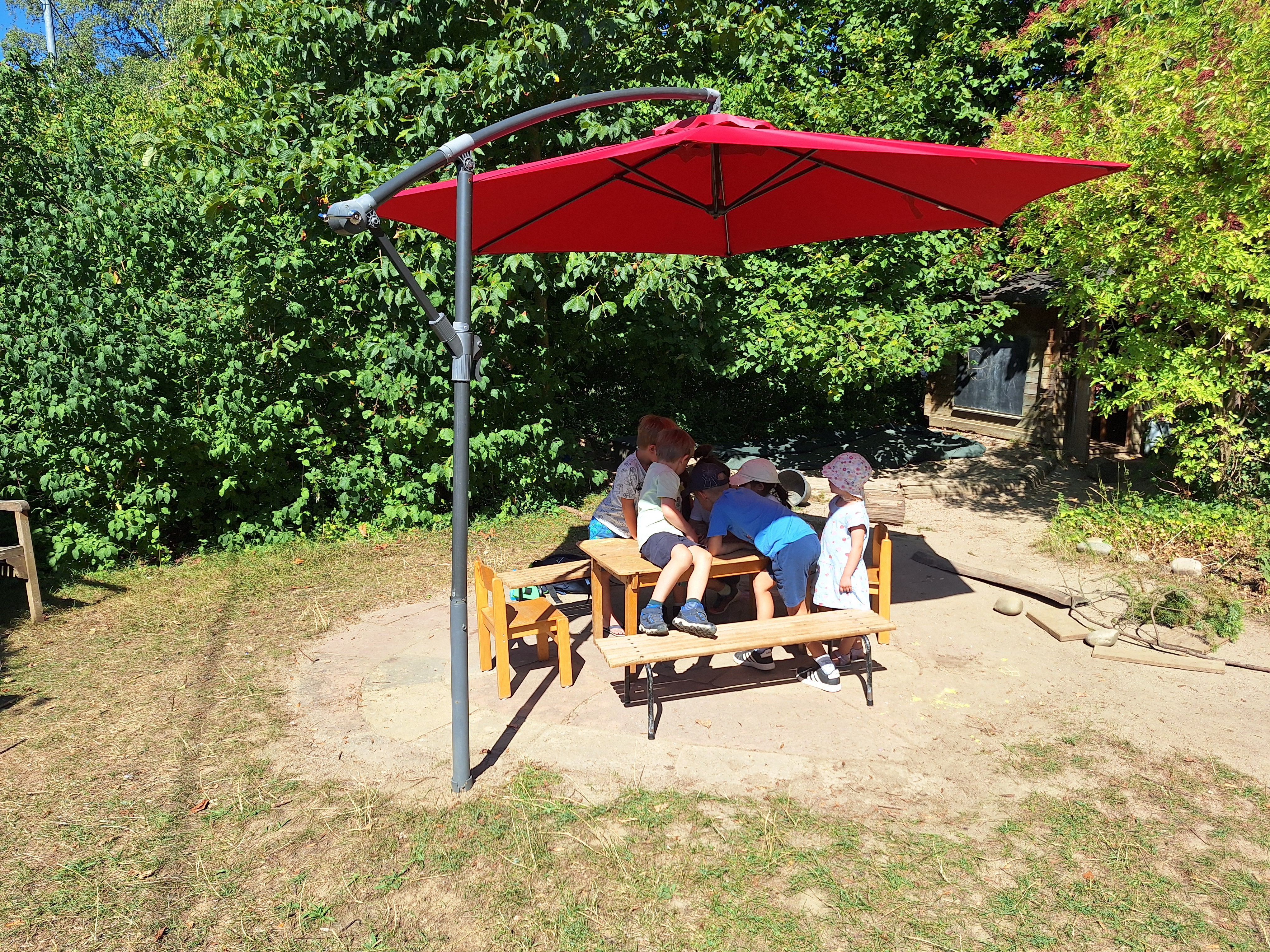 Kinder im Garten unter einem Sonnenschirm