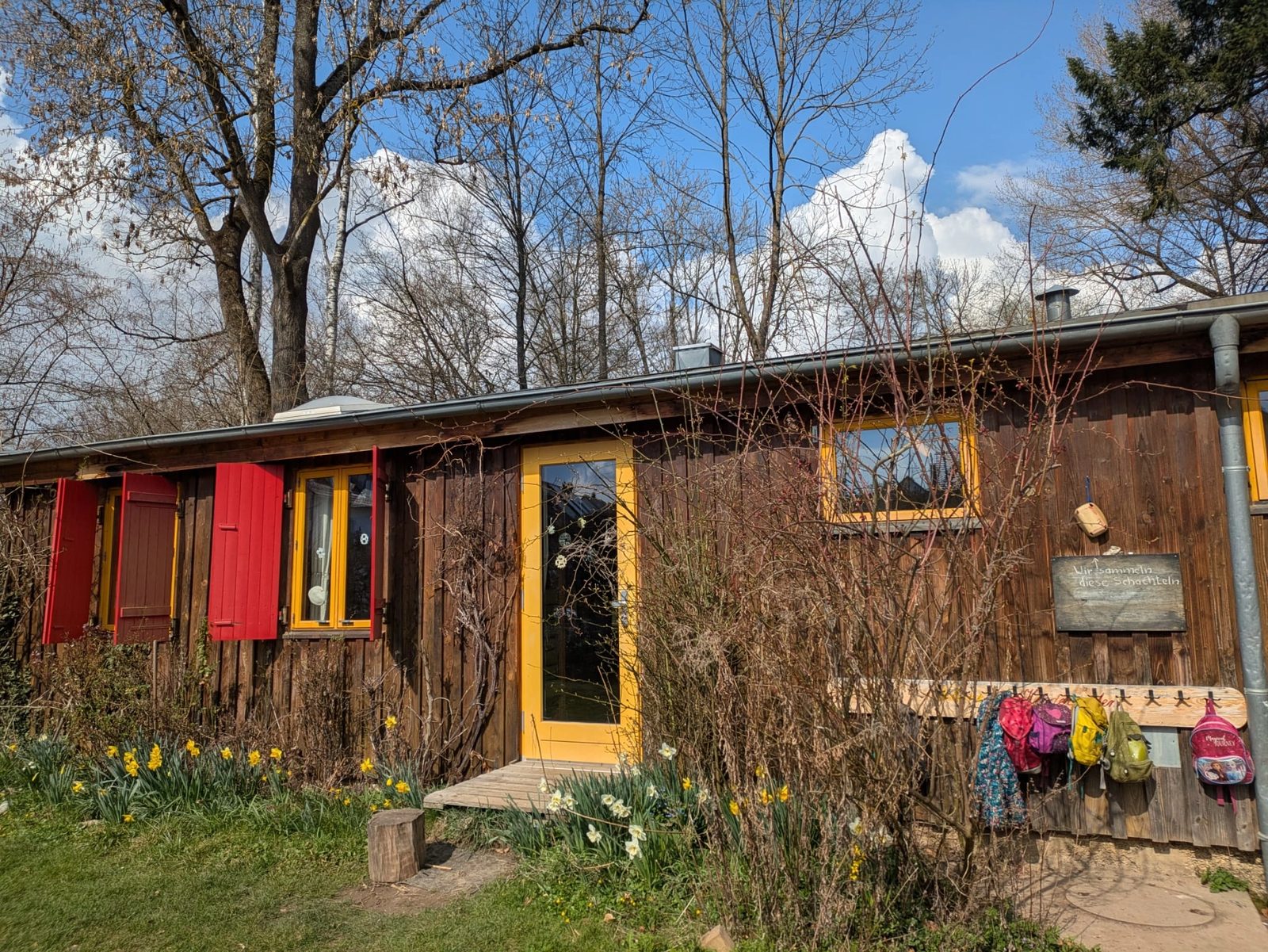 Eingang des Kindergartens mit Kinderrucksäcken und Frühlingsblumen