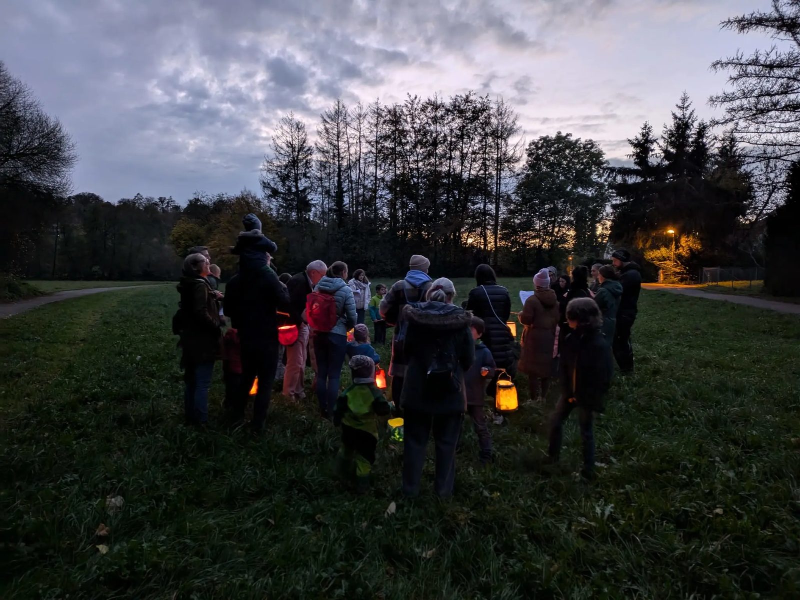 Abendlicher Laternenumzug über eine Wiese