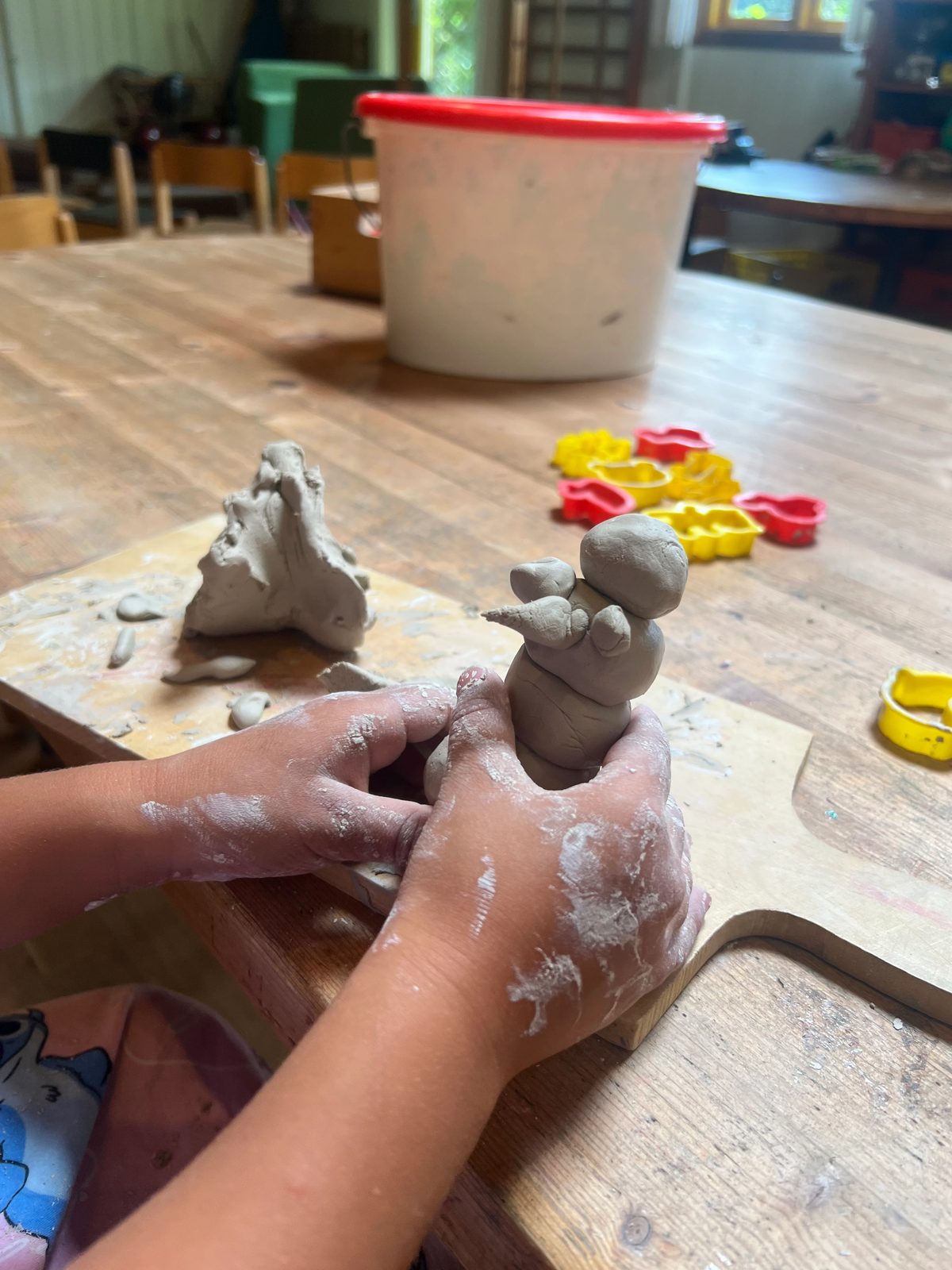 Kinderhände formen eine Figur aus Ton