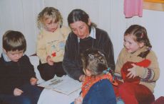 Eine Erzieherin liest mehreren Kindern aus einem Buch vor
